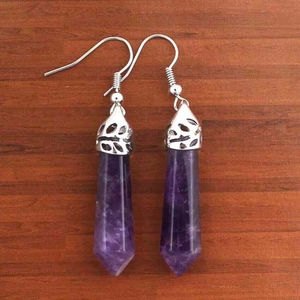 Dettaglio macro di orecchini con cristallo esagonale viola e cappucci in filigrana d'argento