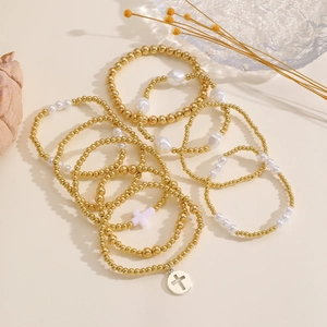 Dettaglio del set di braccialetti fatti a mano con perle dorate e ciondoli a croce