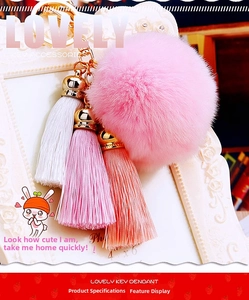 Detailed view of pink plush ball keychain with three-color silk tassels and gold clasp