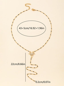 Detailed size view of gold necklace with black beads and rhinestone sunburst pendant