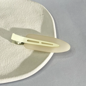 Close-up of a beige matte seamless hair clip on a minimalist ceramic plate