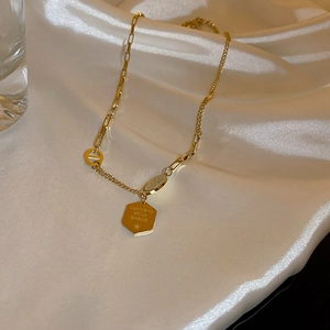 Dettaglio della collana orso in titanio dorato con piastrina su seta bianca