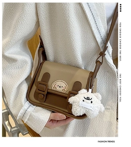 Close-up of retro color-block bag with cute embroidery and a plush mascot pendant