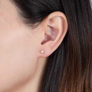 Close-up of a model wearing a gold square white opal stud earring in a minimalist style