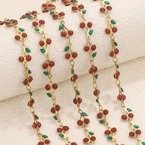 Close-up of red cherry charms with green leaves on a gold stainless steel chain