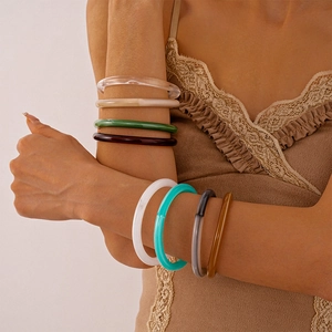 Stack of vintage acrylic resin bangle bracelets in assorted colors on model arm
