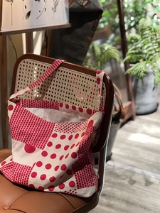 Détail du cabas en toile à pois rouges suspendu à une chaise en bois vintage