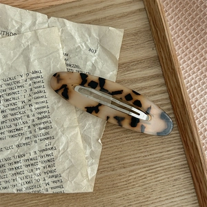 Detail einer ovalen Haarklammer aus Acetat mit Schildpattmuster auf Vintage-Hintergrund