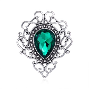 Detail of silver Christmas tree brooch featuring vibrant green gemstones and stones