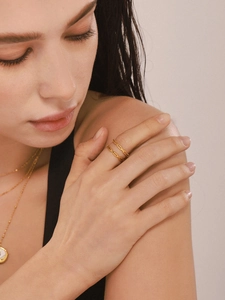 Close-up of minimalist gold plated interlocking rings and layered chains on model