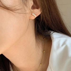 Elegantes Set aus goldener Kugelkette und Perlenohrringen, getragen von einem Modell
