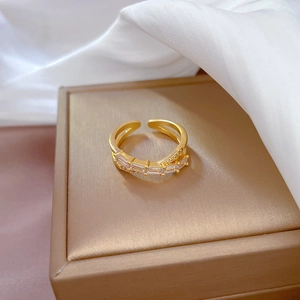 Adjustable gold plated crisscross ring with sparkling cubic zirconia on silk background