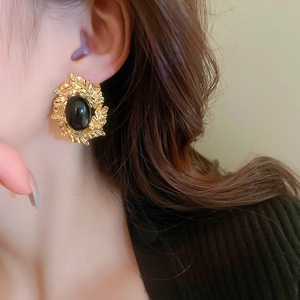 Detail of vintage French style gold leaf earrings with black oval resin stone on ear