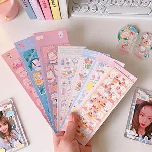 Pastel cartoon bear and rabbit stickers held in a fan shape over a creative desk setup