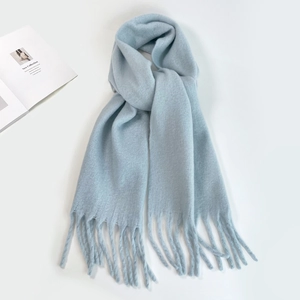 Detail of light blue mohair knit scarf with fringe tassels on a clean white background