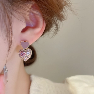 Close-up of heart-shaped earrings with purple enamel and pink sparkling rhinestones
