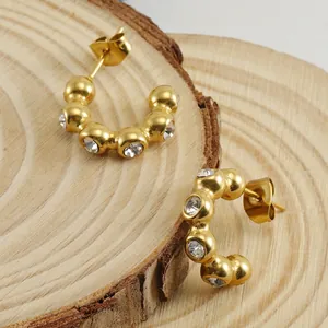 18K gold plated stainless steel U-shaped earrings with clear zircon stones on wood