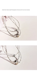 Macro shot of silver cut-bead necklace with grey, black, and white pearls in natural light