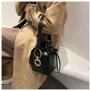 Detailed view of a black cube bucket bag with gold ring handle and drawstring closure