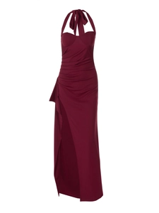 Close-up detail of high-slit hem and draped fabric on a dark red halter maxi dress