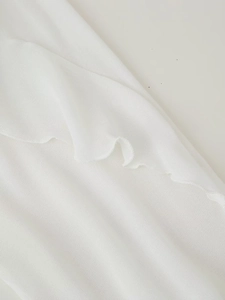 Detailed macro view showing the fine white mesh fabric with elegant layered ruffle textures