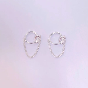 Detail of silver S925 hoop earrings with minimalist metal knot and delicate chain drop