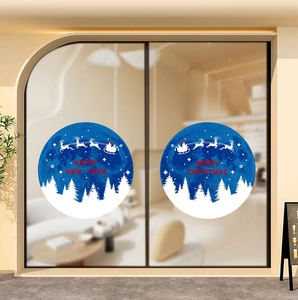 Close-up of blue Christmas window sticker with reindeer sleigh and snowy forest design