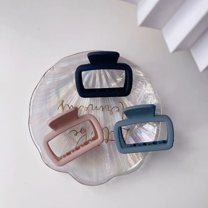 Close-up of three matte square hair claws in navy blue, light pink, and grey blue colors
