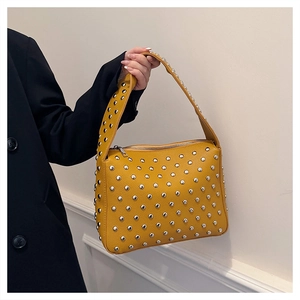 Detail of mustard yellow lychee texture shoulder bag with silver studs and zipper