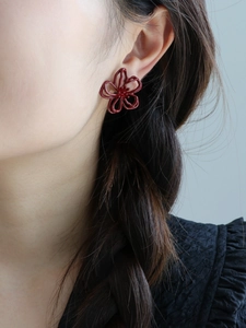 Seitenansicht der eleganten hohlen Blumenohrstecker in Dunkelrot am Modellohr