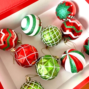 Detailed view of red and green painted Christmas ball ornaments with glitter patterns