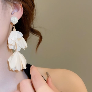Close-up of white chiffon flower petal tassel earrings on a model with gold studs
