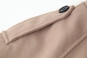 Detailed macro view of khaki wool coat shoulder strap with black button and fine stitching