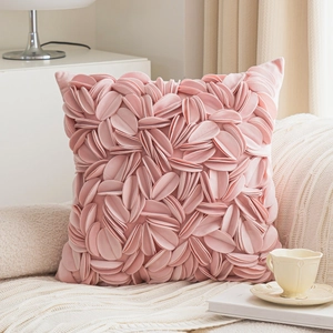 Pink 3D floral petal throw pillow cover on a beige sofa with a cozy cream blanket
