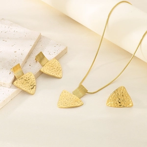 Detailed view of 18K gold plated jewelry set with geometric hammered texture on fabric