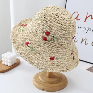 Detail of hand-woven beige straw hat featuring delicate red tulip floral embroidery
