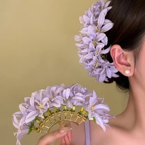 Detailed view of elegant purple fabric flower hair fork with gold base worn by an Asian model