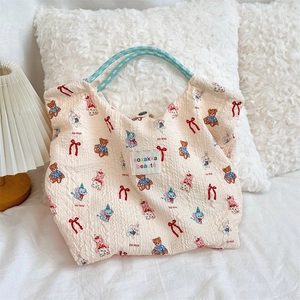 Detail of cream pleated canvas tote bag with cute animal prints and blue braided handle