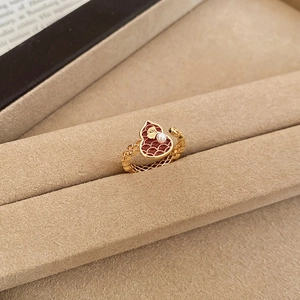 Close-up of 18k gold plated ring with red enamel gourd and a small white pearl detail