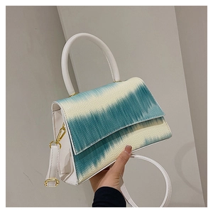 Detail of white crossbody bag with blue tie-dye pattern and golden hardware hooks