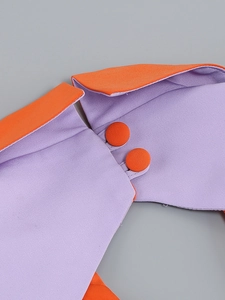 Detail of purple dress fabric with orange trim and two matching buttons in close-up shot
