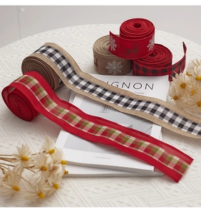 Close-up of rustic Christmas ribbon rolls with snowflake and plaid patterns on white cloth