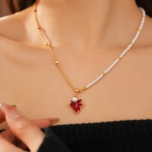 Gros plan du collier asymétrique plaqué or 18K avec pendentif feuille et perles blanches