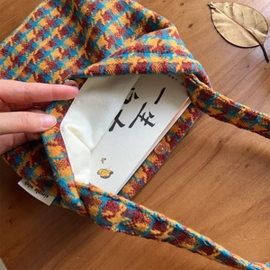 Detail of vintage houndstooth knit tote bag with magnetic clasp on a rustic wooden desk