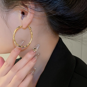 Close-up of 14k gold plated twisted hoop earrings worn for a stylish fashion look