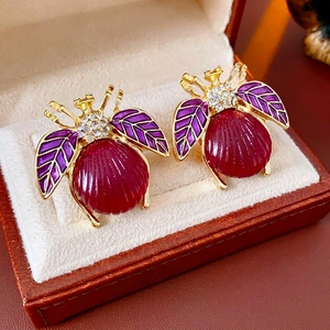 Vintage beetle stud earrings with purple enamel wings and red crystal inlay in a jewelry box