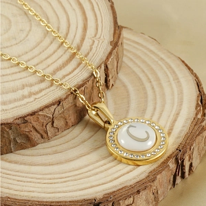 Vue macro du pendentif doré avec lettre C incrustée de cristaux sur bois