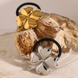 Polished gold and silver 3D clover hair ties on natural stone display for women