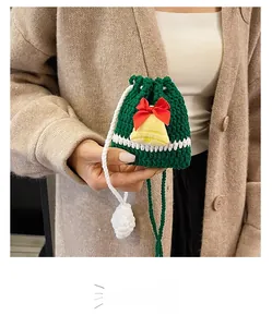 Close-up of handmade green crochet Christmas reindeer bag with yellow bell and red ribbon