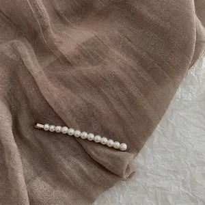 Macro detail of elegant baroque hair clip with 13 glossy white pearls on a metal base